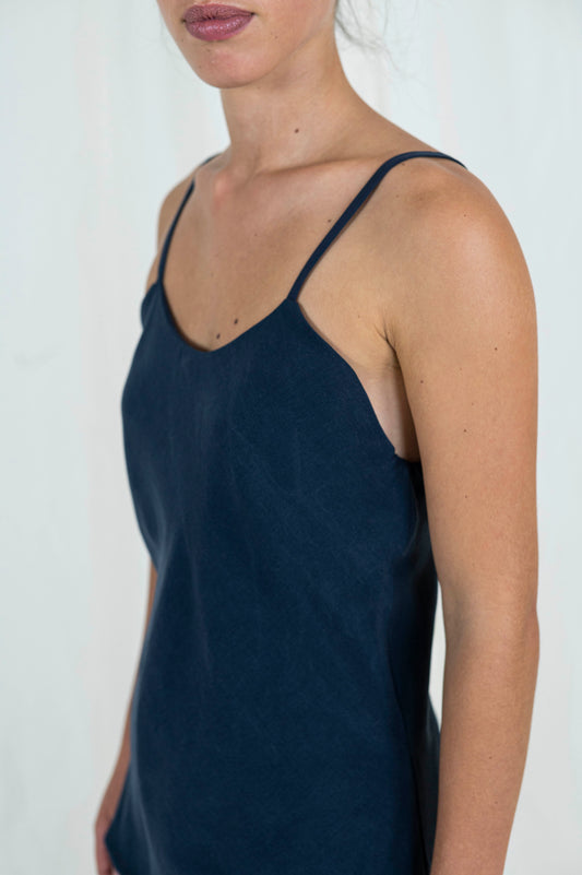 Close up view of woman wearing bias cut camisole tank top in dark indigo tencel fabric. 